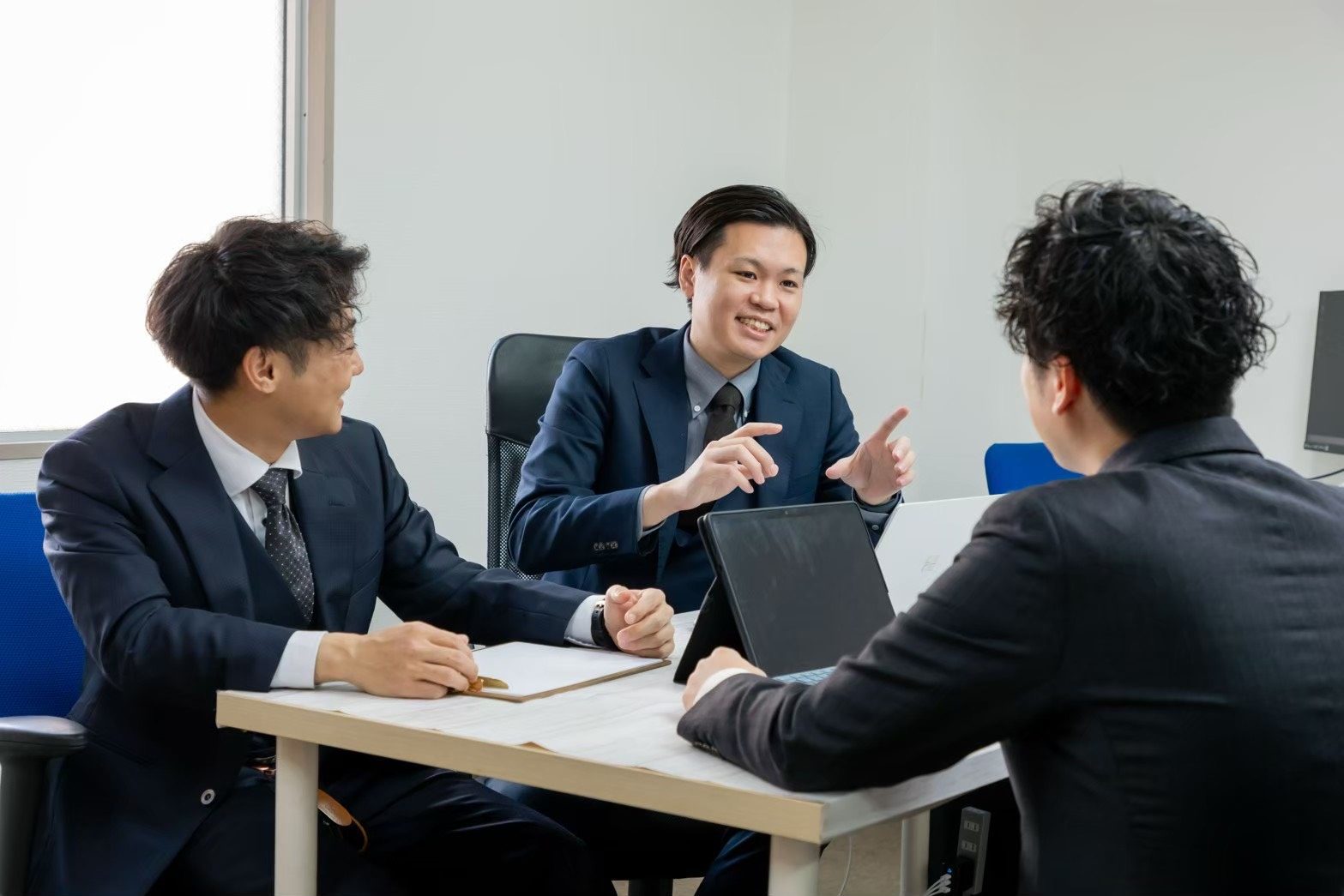 オフィスでタブレットを囲みながら打ち合わせをするBLAYNのメンバー